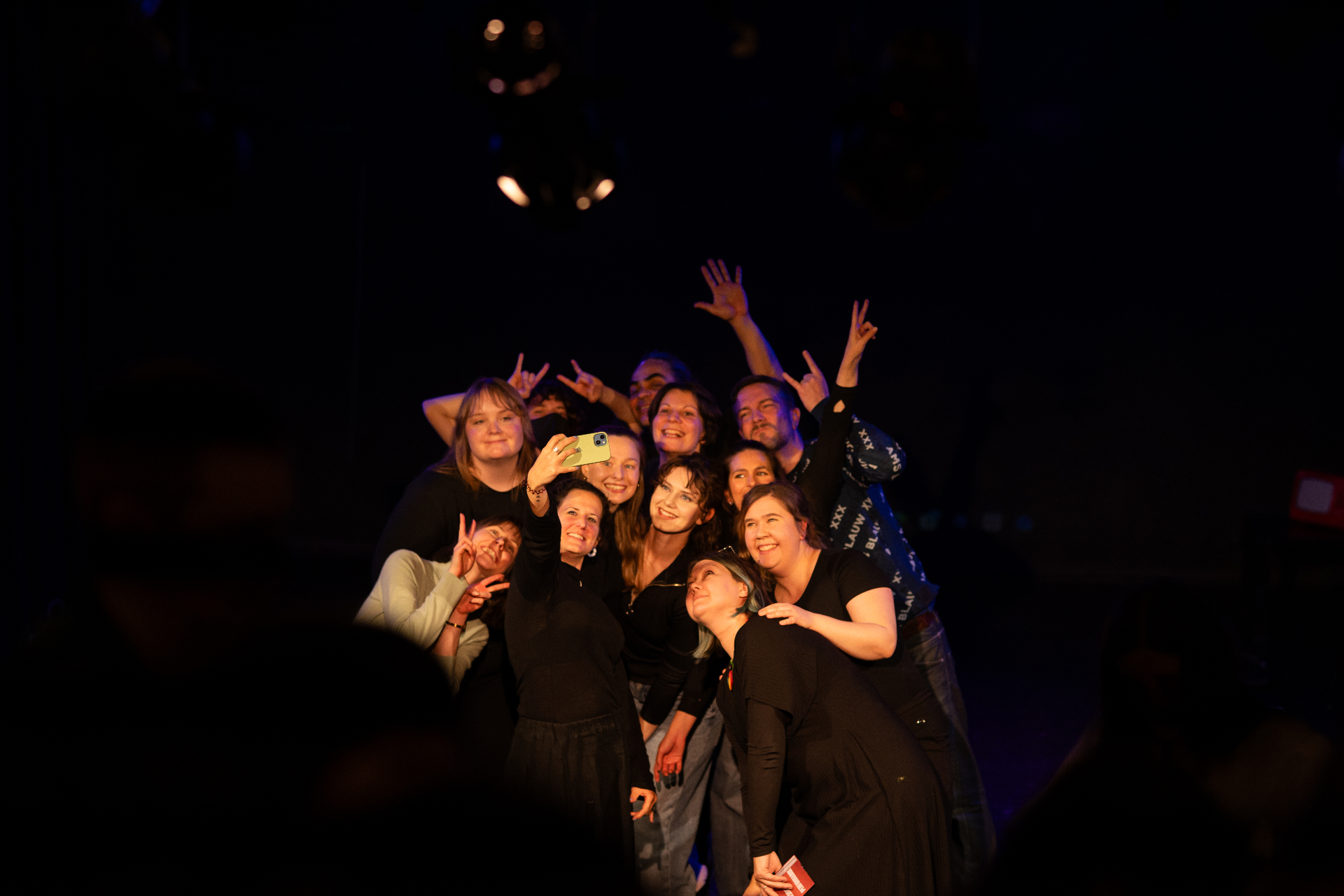 Ensemble taking a joyful group selfie on stage after the show